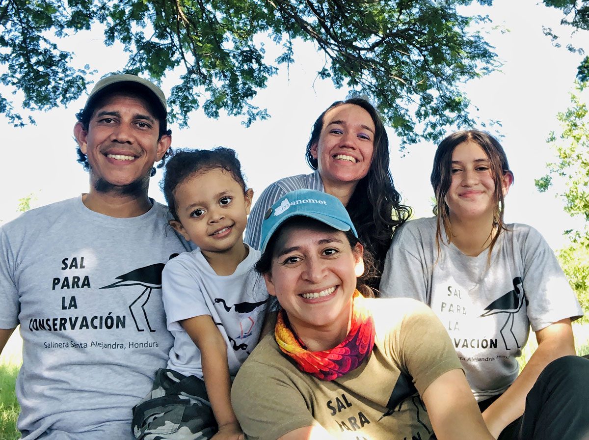 four adults and one child smile at the camera, wearing shirts that say "Sal Para La Conservacion."
