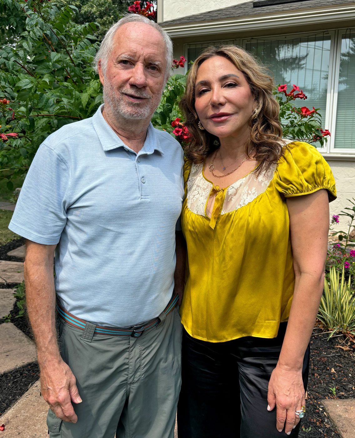 A man and woman stand in a garden.