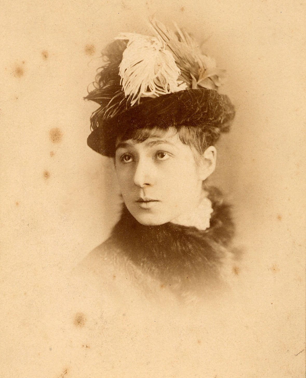 Old photo of a women wearing a bat and coat collar of bird feathers