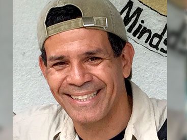 Smiling man with backwards baseball cap.