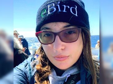 Woman with sunglasses and beanie that says "eBird."