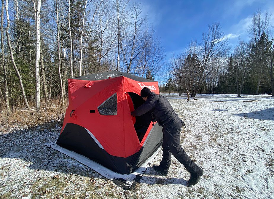 A red tent on a snowy, forested landscape.