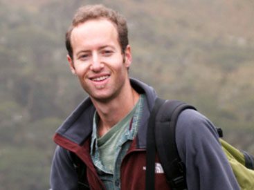 Smiling man with a jacket and backpack.