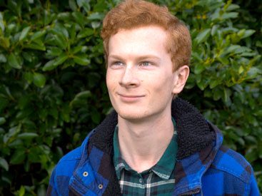 Red-haired young man with blue jacket and plaid shirt.