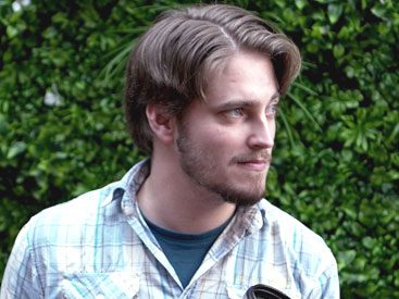 Young man in plaid shirt, looks to the side.